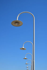 Low angle view of street lights against clear blue sky