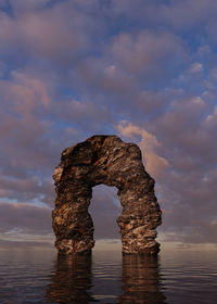 Rock formation in sea against sky