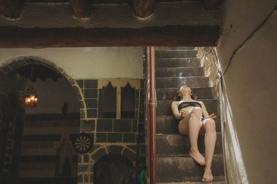 High angle view of shirtless woman sitting in building