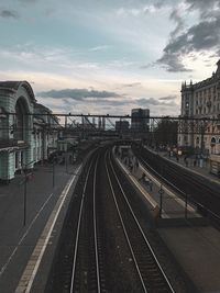 Railroad tracks in city against sky at sunset