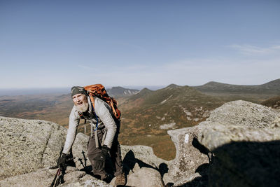 A retired hiker struggles over rocks as he climbs mount katahdin
