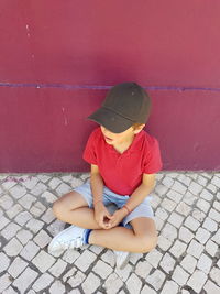 Full length of boy sitting on sidewalk