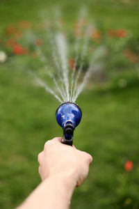 Gardener's hand holds a hose with a sprayer and watered the plants in the garden