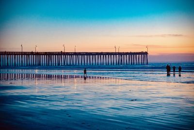 Silhouette pier on beach against sky during sunset