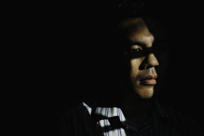 Close-up of young woman against black background