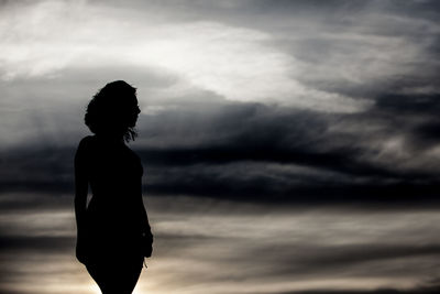 Rear view of silhouette woman standing against sky