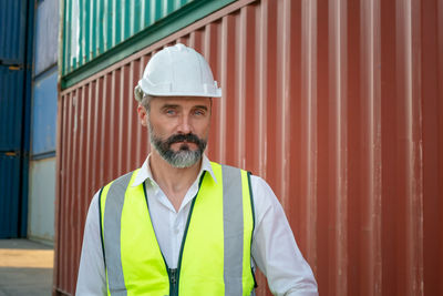 Portrait of young man standing against wall