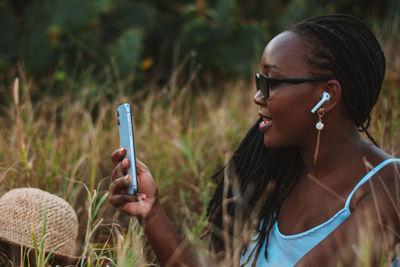 Young woman using mobile phone against grass and cactus trees 