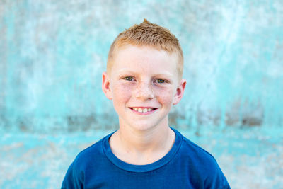 Portrait of a red head boy with freckles with a blue background