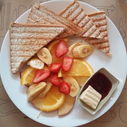 Directly above shot of fruits and breads served in plate on table