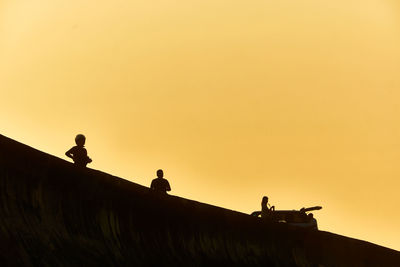 Low angle view of silhouette people walking on mountain against clear sky