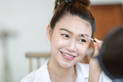 Smiling woman applying make-up