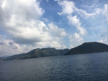 Scenic view of sea by mountains against sky