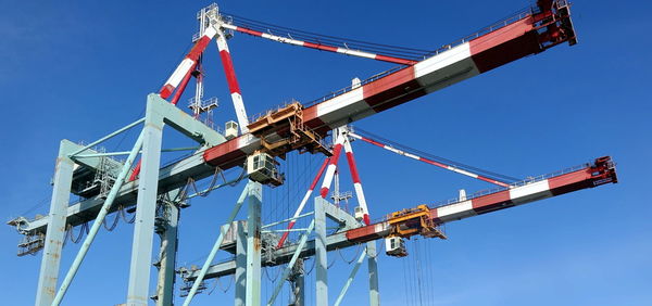 Low angle view of crane against clear blue sky