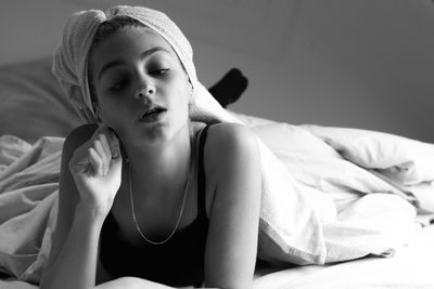 Portrait of young woman sitting on bed at home