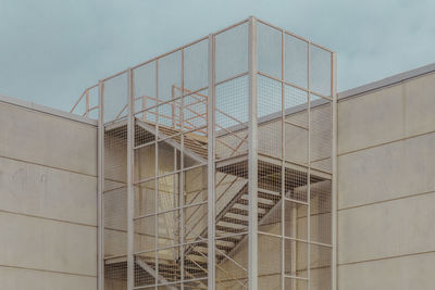 Metallic industrial ladder on wall against sky