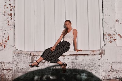 Portrait of young woman against wall