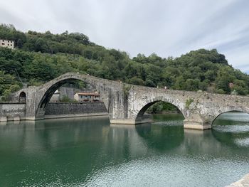 Arch bridge over river against sky