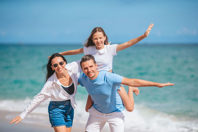 Full length of young woman with arms raised standing at beach