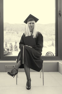 Full length of woman wearing graduation gown standing in the dark