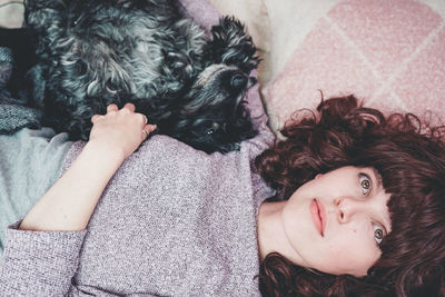 Woman with dog lying on bed at home