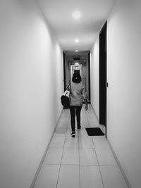 Rear view of woman walking in illuminated corridor