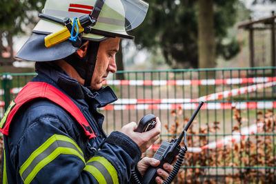 Side view of firefighter standing by fence