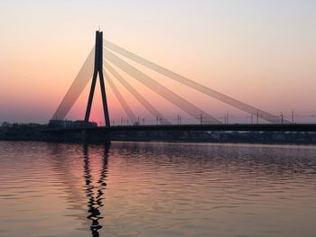 Suspension bridge over river against sky during sunset