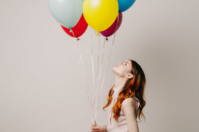 Young woman looking away while standing against white background