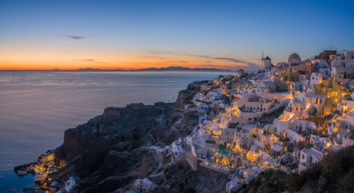 High angle view of sea and buildings against sky at sunset