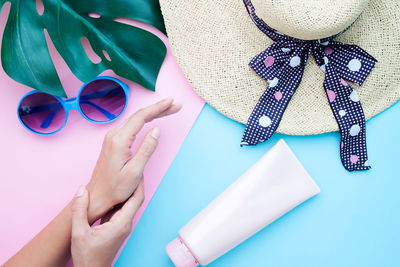 Cropped woman hands by hat and moisturizer on table