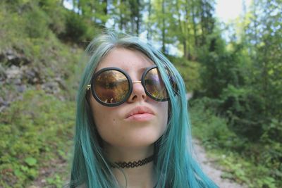 Close-up portrait of woman in sunglasses against trees