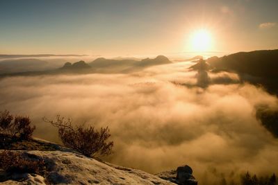 Fantastic colorful sunrise on the top of the rocky mountain with the view into misty valley