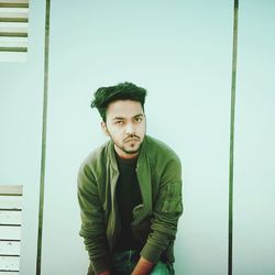 Portrait of young man standing against wall