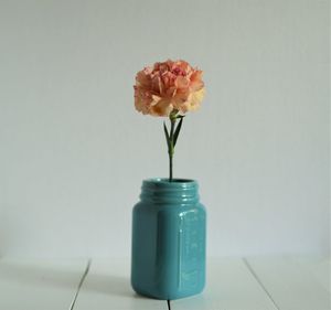 Close-up of orange carnation in jar on table at home