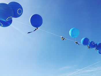 Low angle view of hot air balloons flying against blue sky