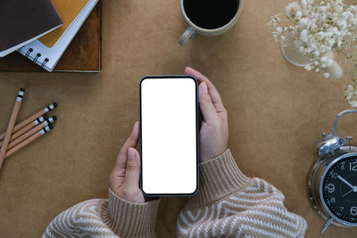 High angle view of woman using mobile phone on table