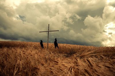 People standing on field against cloudy sky