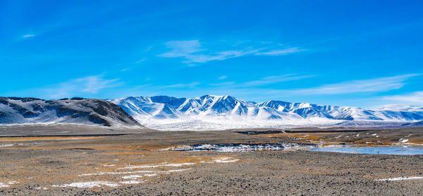 Scenic view of snowcapped mountains against blue sky