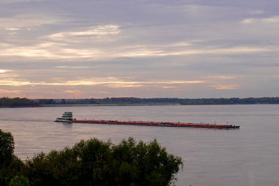 Boat sailing in river against sky during sunset