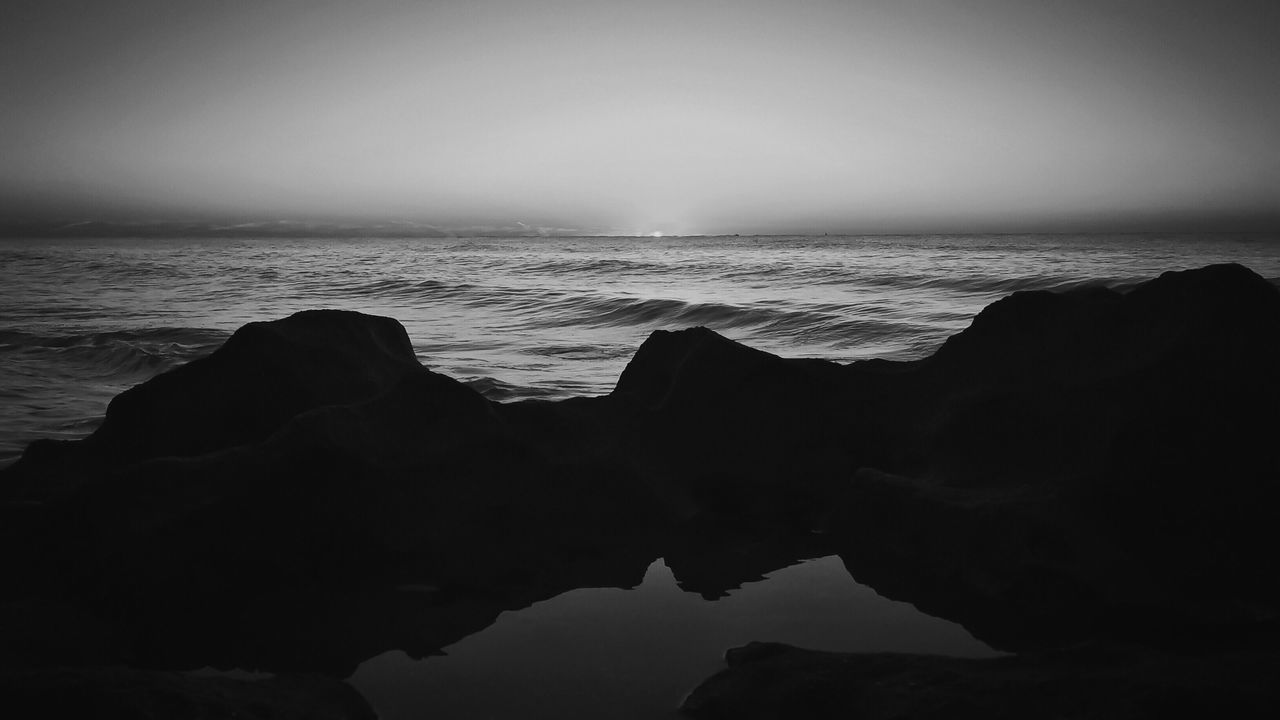 sea, water, horizon over water, tranquil scene, scenics, tranquility, clear sky, beauty in nature, copy space, rock - object, nature, idyllic, rock formation, silhouette, sky, calm, reflection, shore, rock, beach