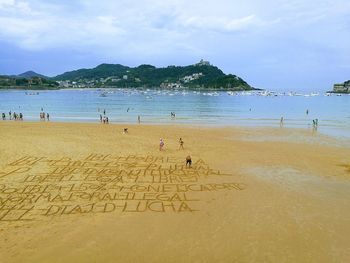 People playing on beach against sky