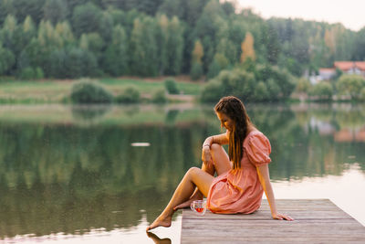 Side view of woman sitting on pier