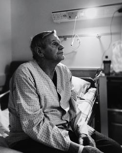 Senior man sitting on bed at hospital