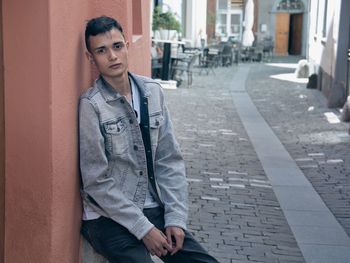 Portrait of teenage boy sitting against wall