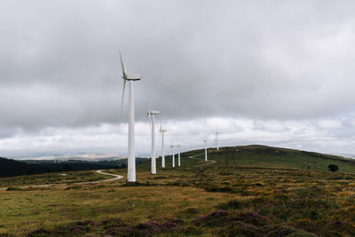 Wind turbines on field against sky