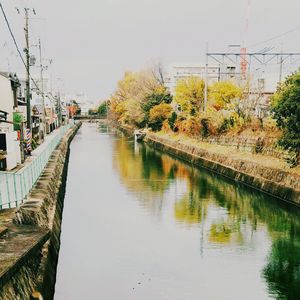 Footbridge over river in city against clear sky