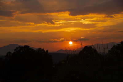 Scenic view of silhouette mountains against orange sky