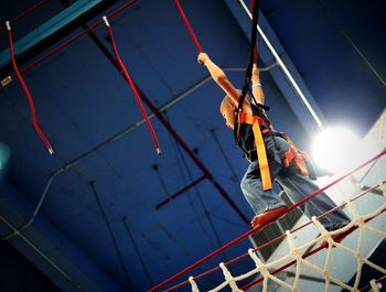 Low angle view of boy hanging from ropes