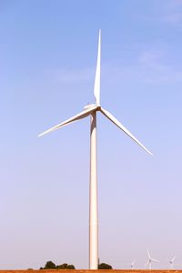 Low angle view of wind turbine against blue sky